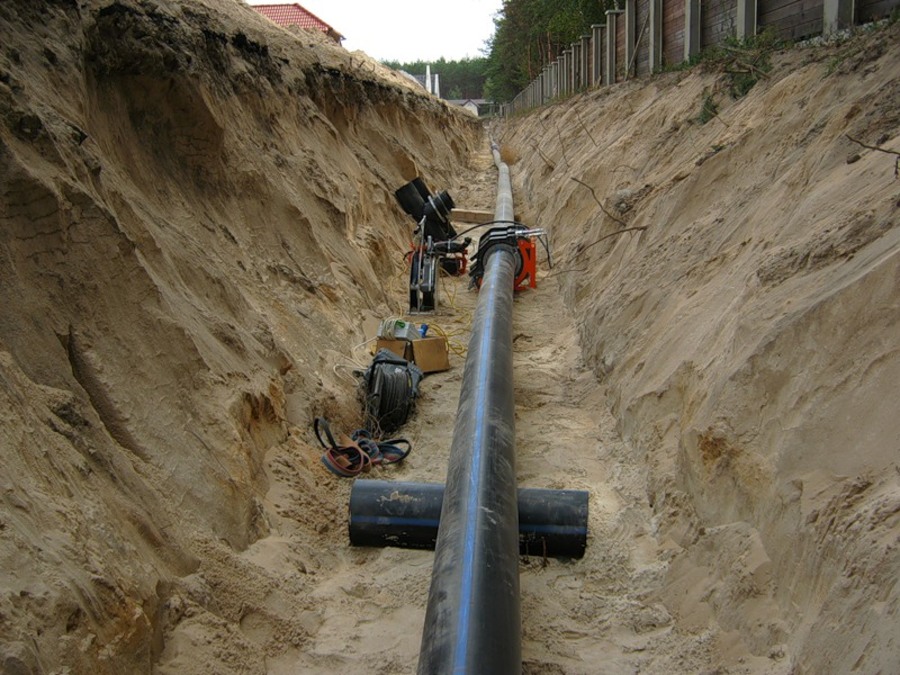 Строительство подземного газопровода. Водопроводная труба 150мм в траншее. Прокладка труб ПНД d110. Прокладка ПНД 110 В траншеи. Прокладка трубы 110 в траншее.